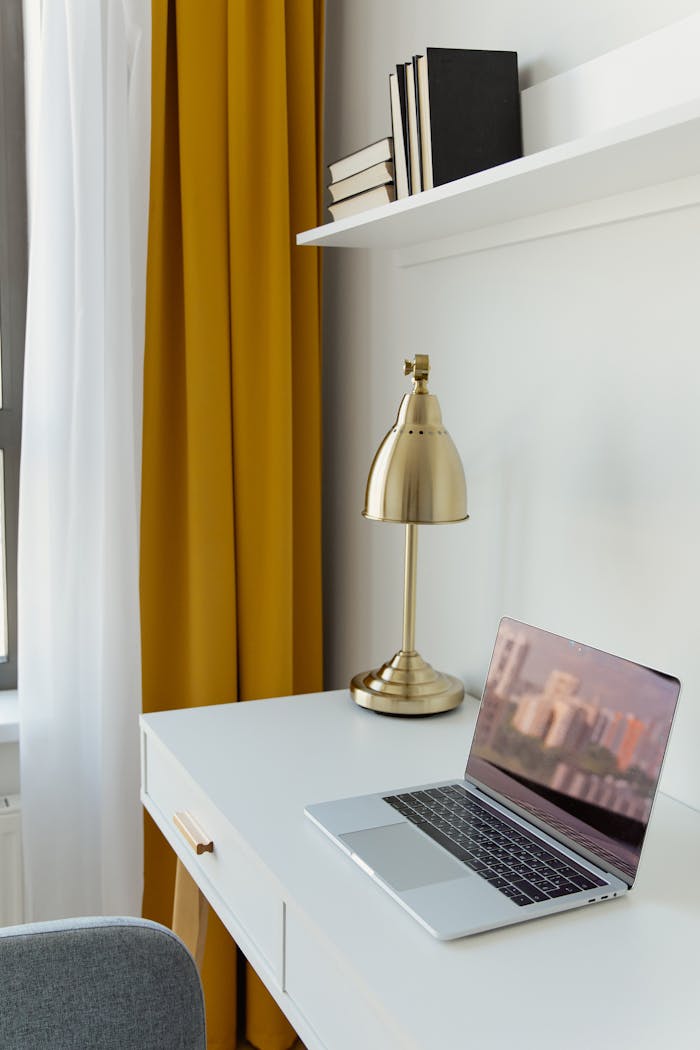 Stylish home office featuring a minimalist desk and a metallic lamp with bold yellow curtains for a contemporary look.